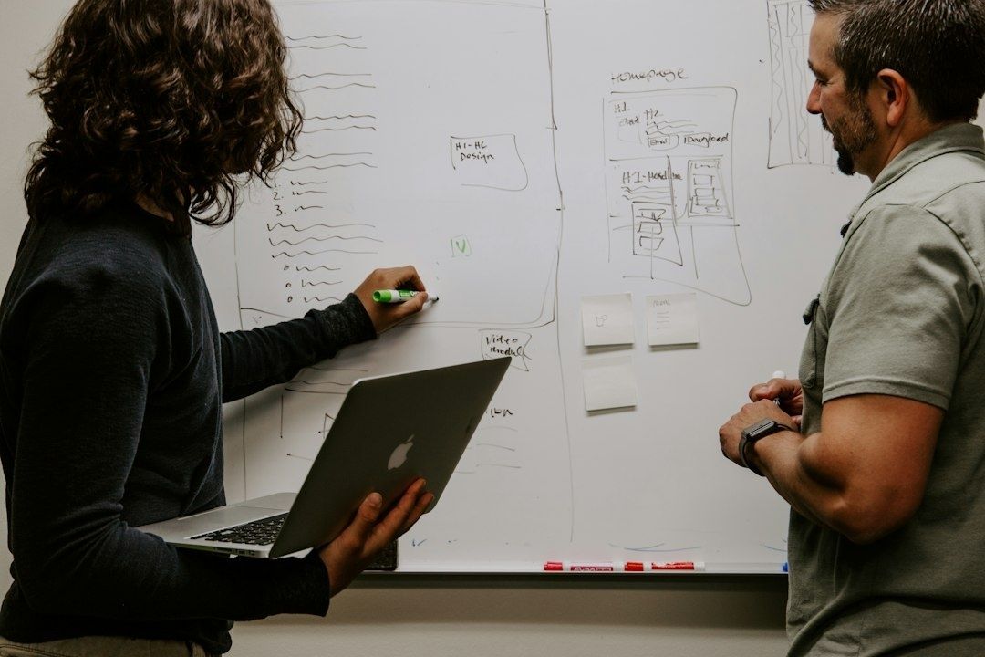 Två personer diskuterar systemdesign framför en skissad whiteboard